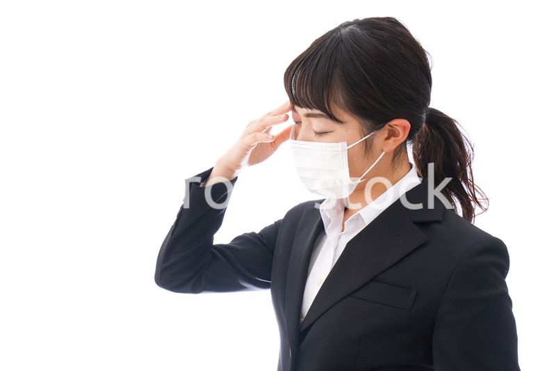 花粉症・風邪・インフルエンザに苦しみマスクをする若い女性