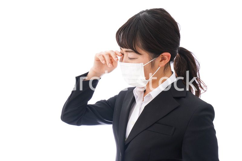 花粉症・風邪・インフルエンザに苦しみマスクをする若い女性