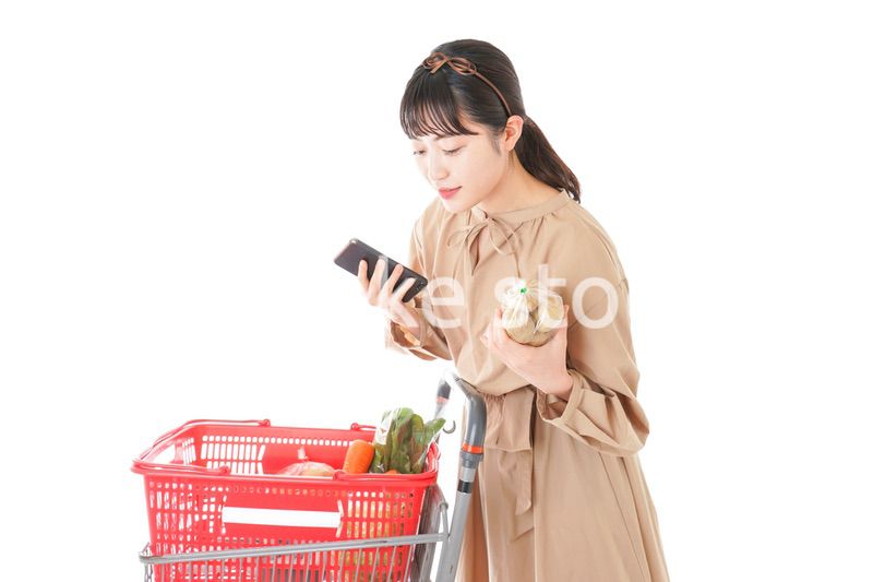 スーパーで食品の原産地を調べる若い女性