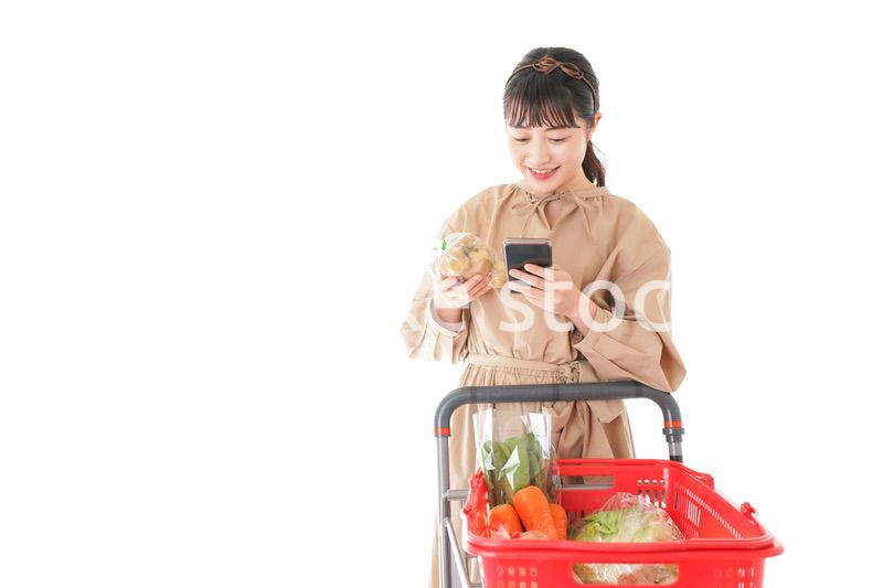 スーパーで食品の原産地を調べる若い女性