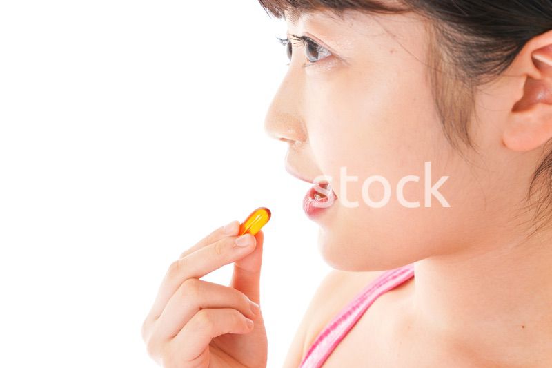 薬・サプリメントを服用する若い女性