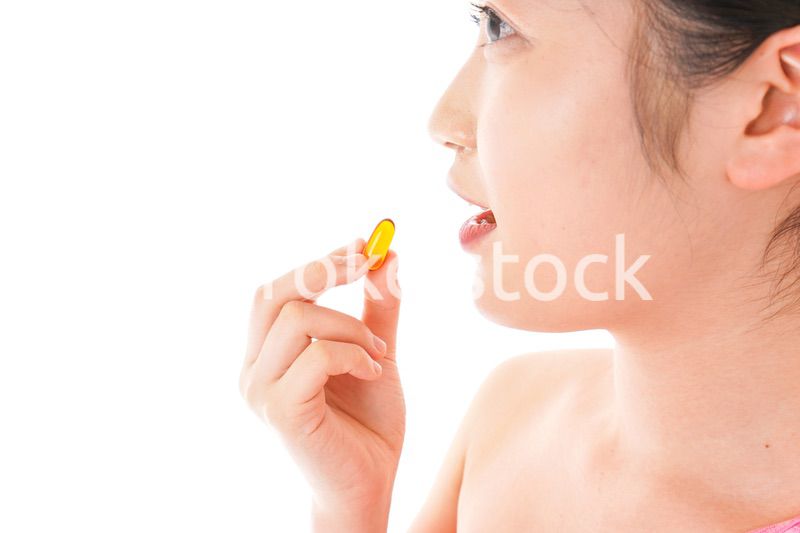 薬・サプリメントを服用する若い女性