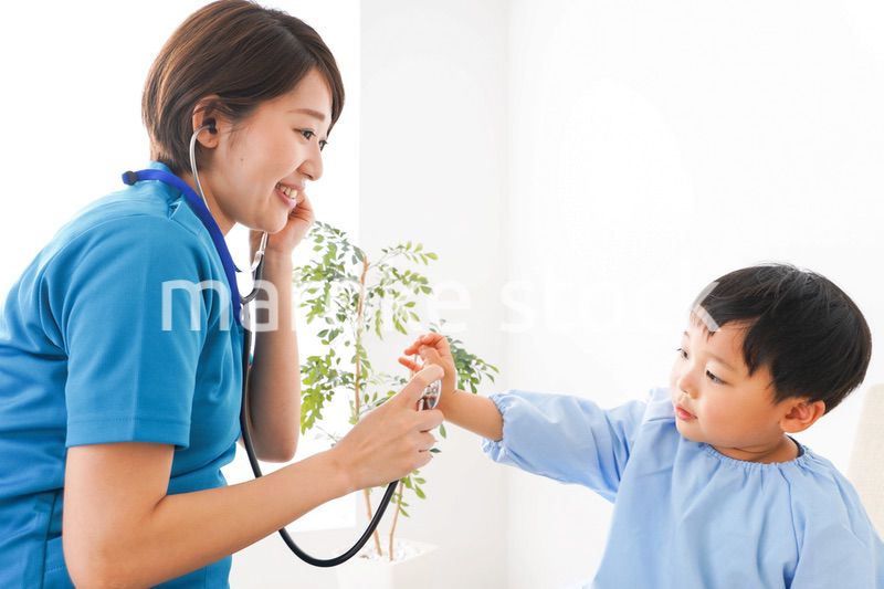 子どもを診察する若い看護師