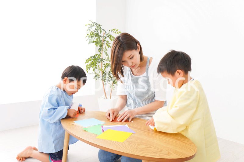 幼稚園で折り紙をする子どもと先生
