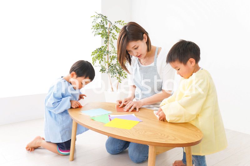 幼稚園で折り紙をする子どもと先生