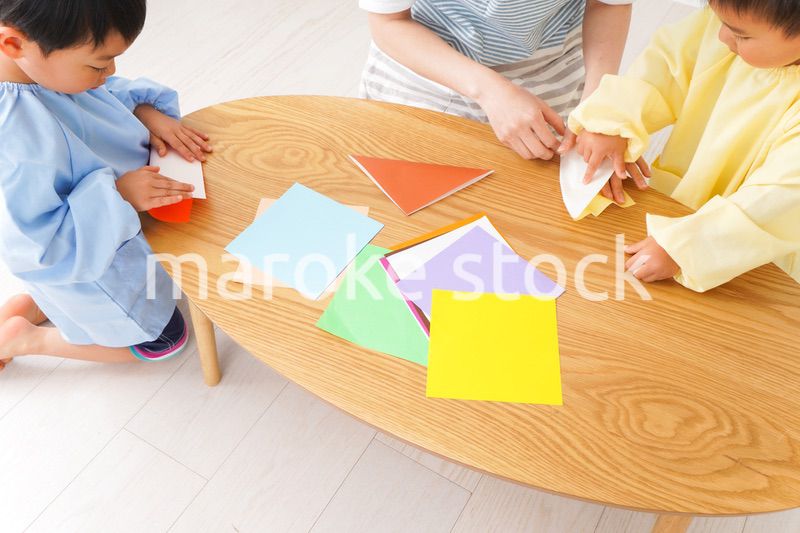 幼稚園で折り紙をする子どもと先生