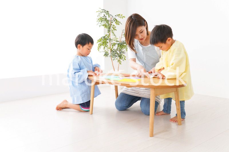 幼稚園で折り紙をする子どもと先生