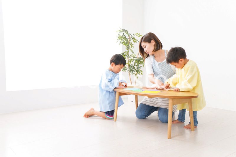 幼稚園で折り紙をする子どもと先生