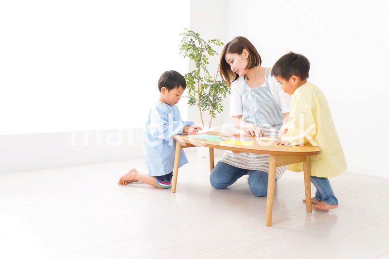 幼稚園で折り紙をする子どもと先生