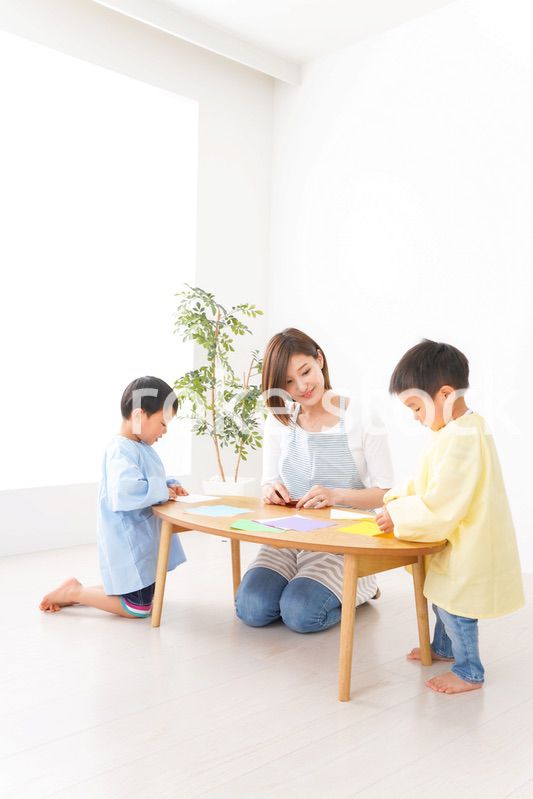 幼稚園で折り紙をする子どもと先生