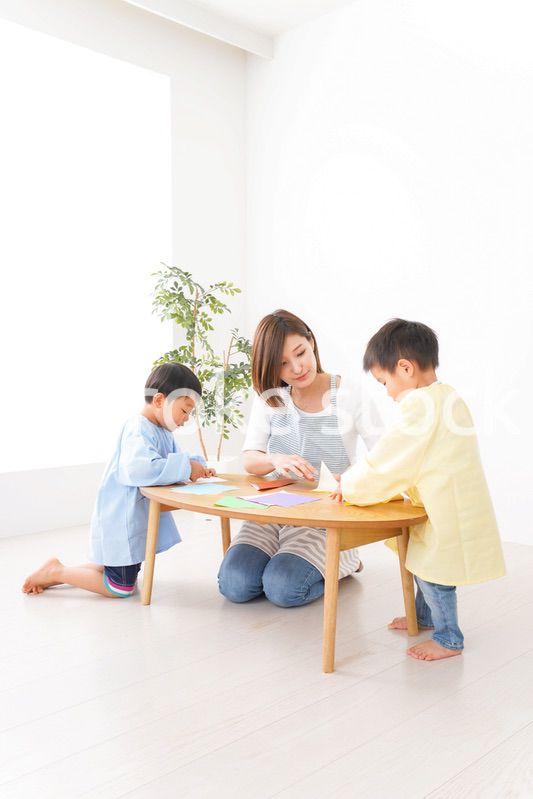 幼稚園で折り紙をする子どもと先生