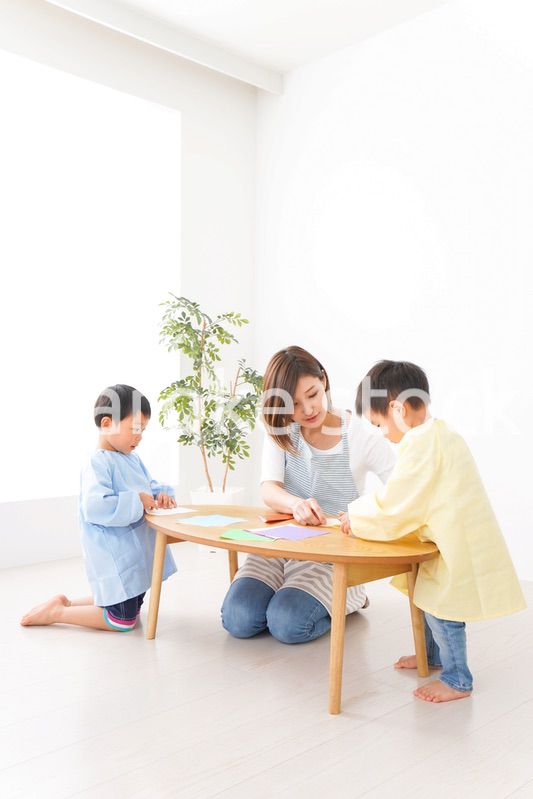 幼稚園で折り紙をする子どもと先生