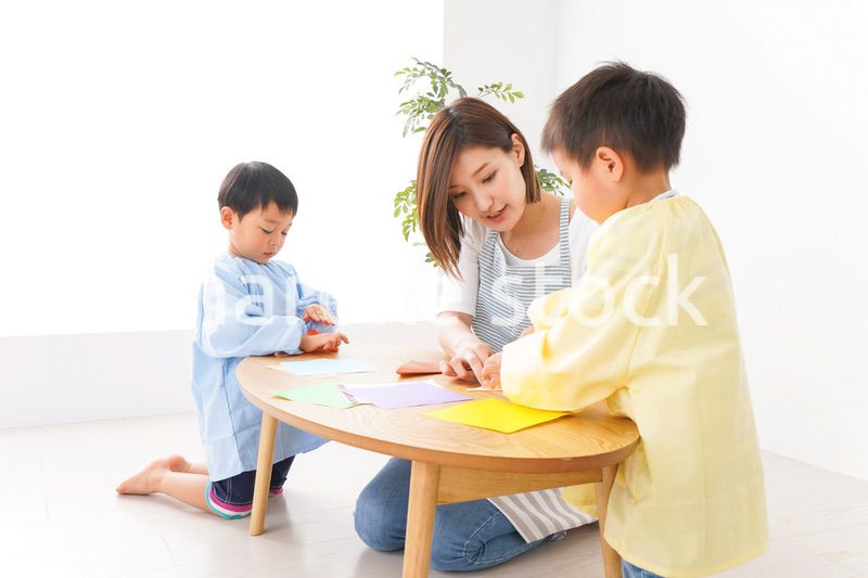 幼稚園で折り紙をする子どもと先生
