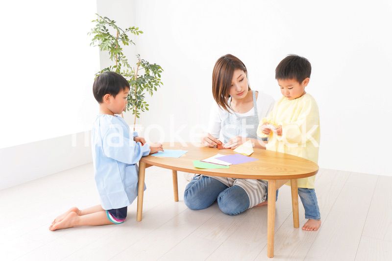 幼稚園で折り紙をする子どもと先生