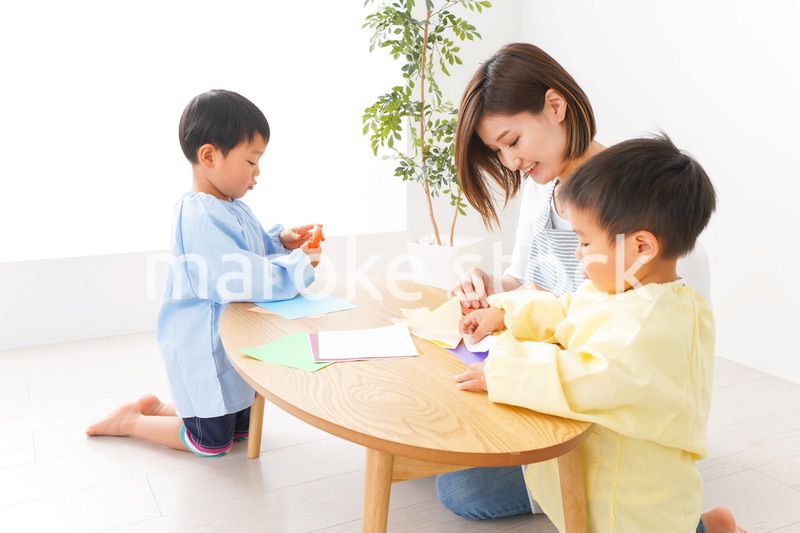 幼稚園で折り紙をする子どもと先生