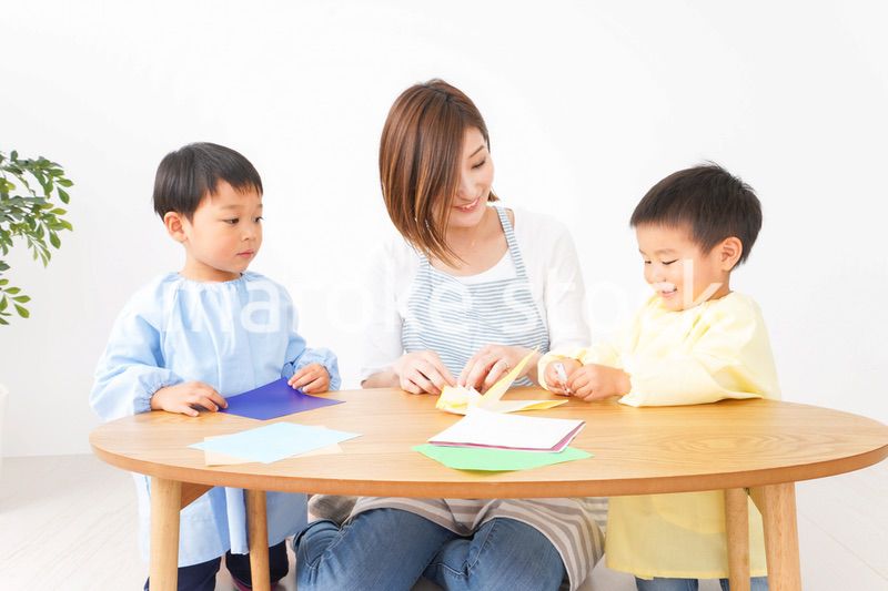 幼稚園で折り紙をする子どもと先生