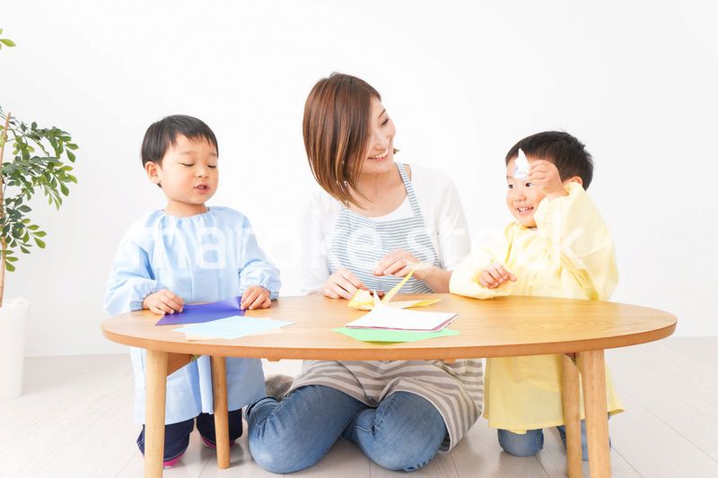 幼稚園で折り紙をする子どもと先生