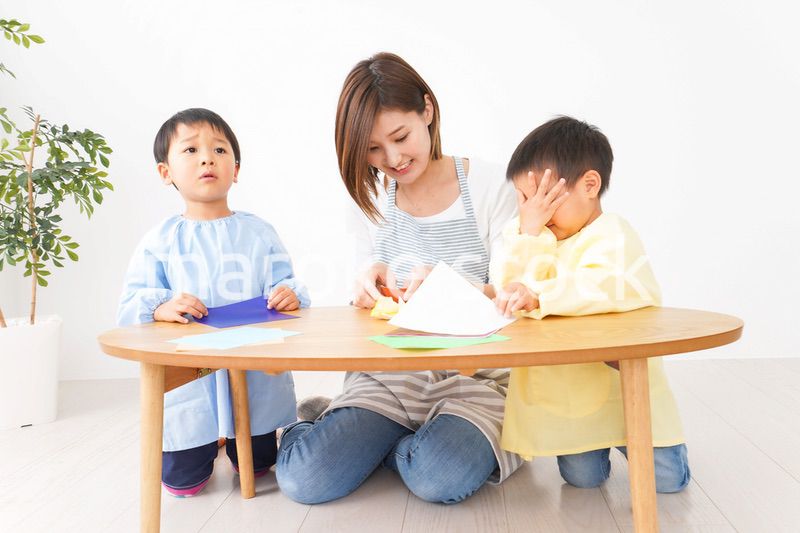 幼稚園で折り紙をする子どもと先生