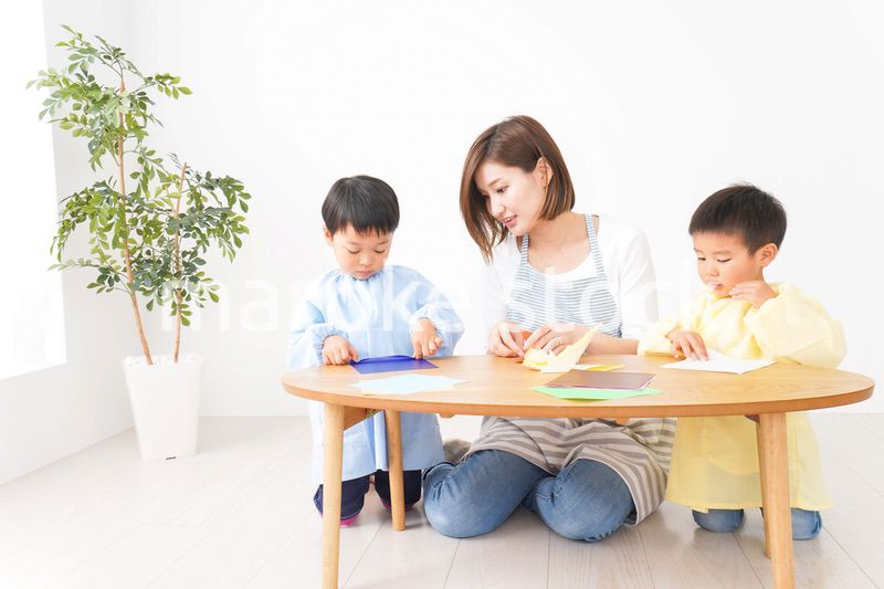 幼稚園で折り紙をする子どもと先生