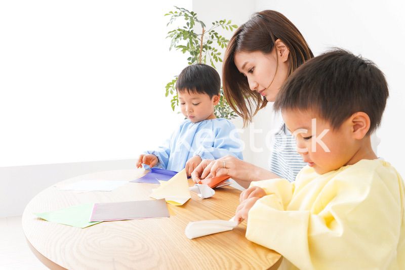 幼稚園で折り紙をする子どもと先生