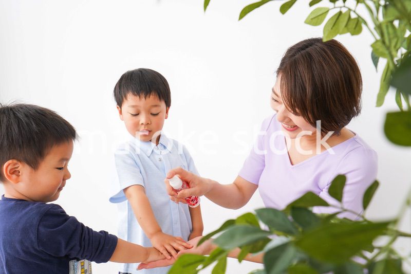 除菌スプレーを子どもにかけるお母さん