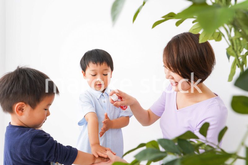 除菌スプレーを子どもにかけるお母さん