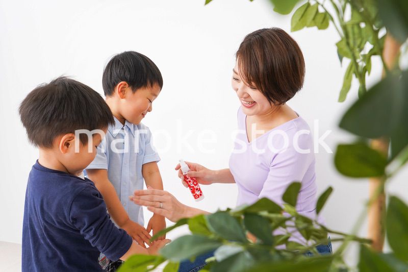 除菌スプレーを子どもにかけるお母さん