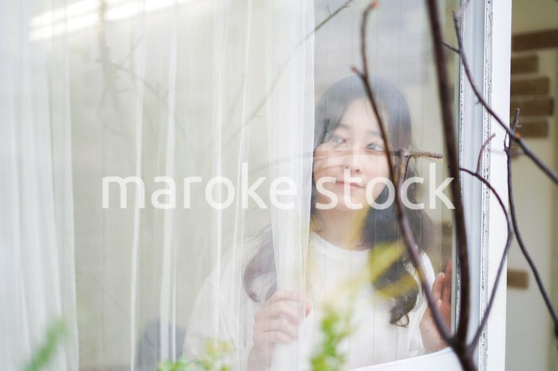 外の天気を確認する若い女性