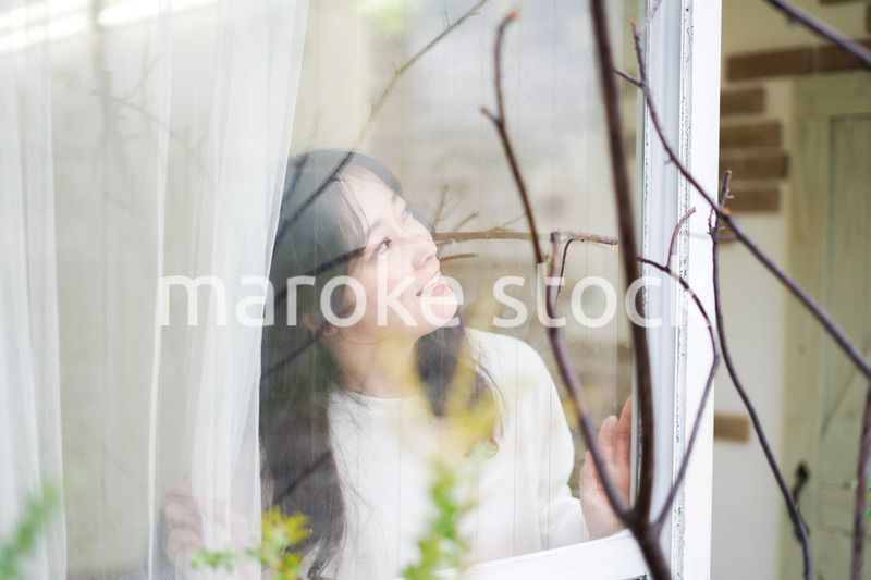 外の天気を確認する若い女性