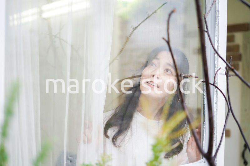 外の天気を確認する若い女性