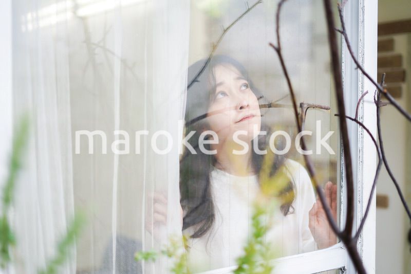 外の天気を確認する若い女性