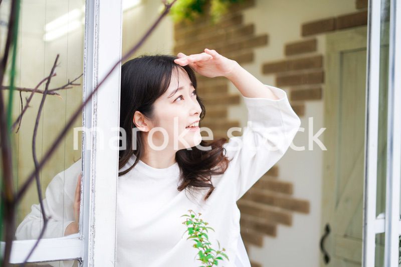 外の天気を確認する若い女性