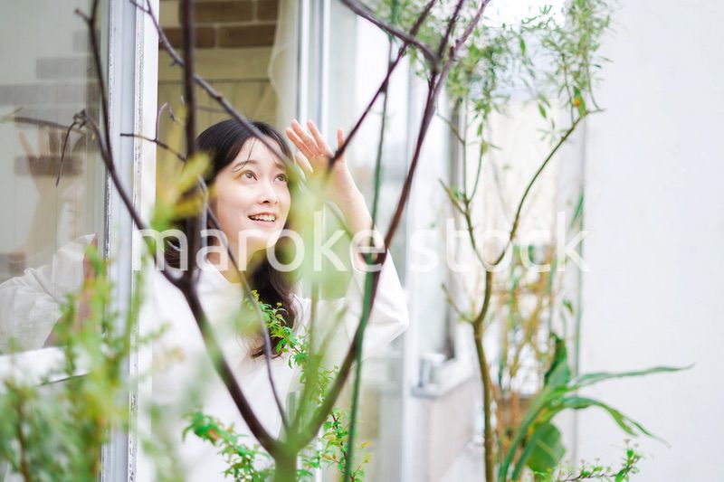 外の天気を確認する若い女性