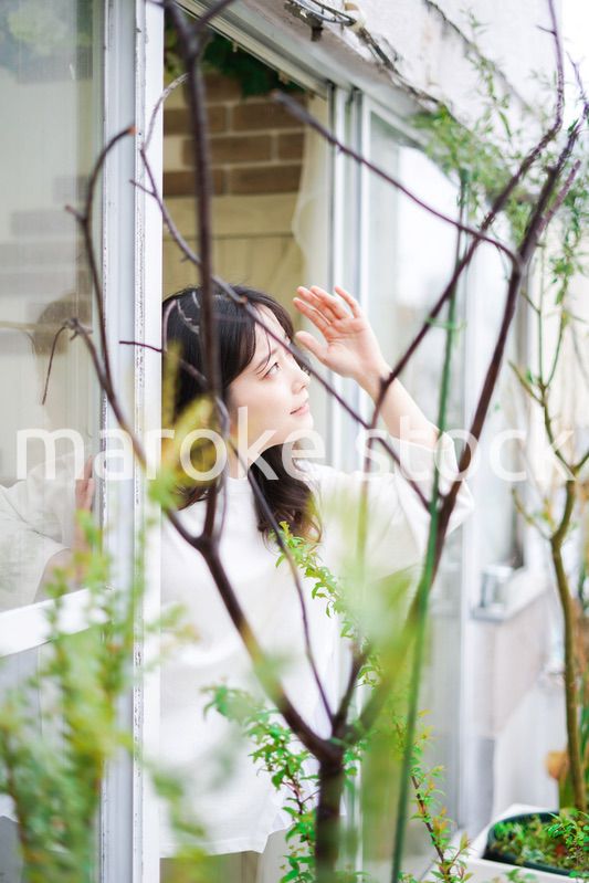 外の天気を確認する若い女性