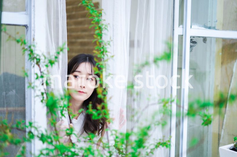 外の天気を確認する若い女性