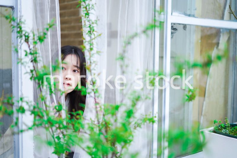 外の天気を確認する若い女性