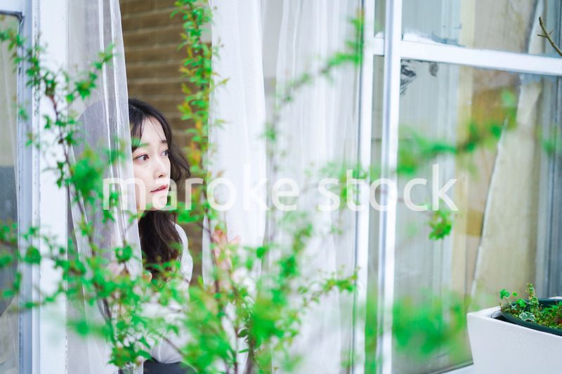 外の天気を確認する若い女性