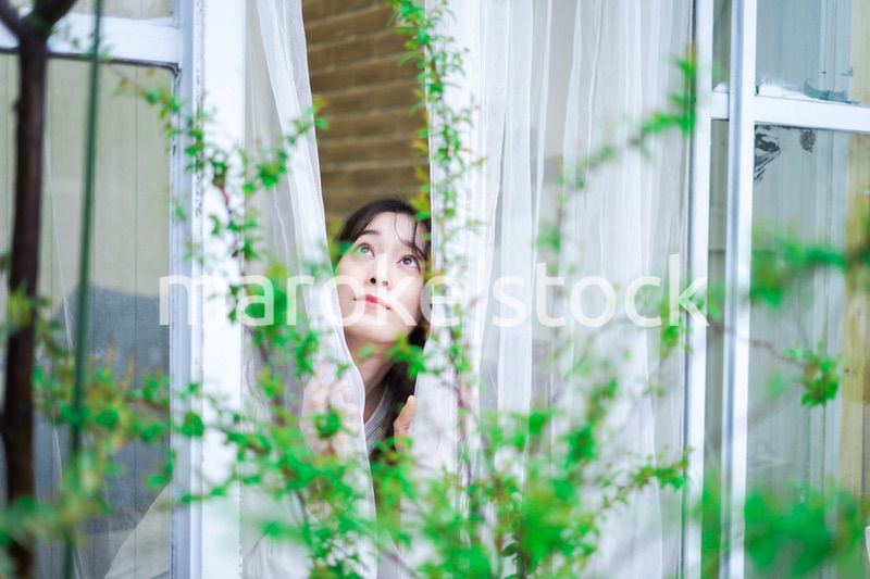 外の天気を確認する若い女性