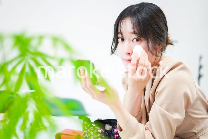 笑顔でメイクをする若い女性