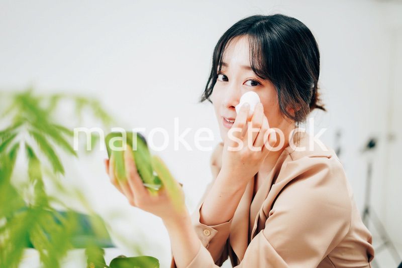 笑顔でメイクをする若い女性