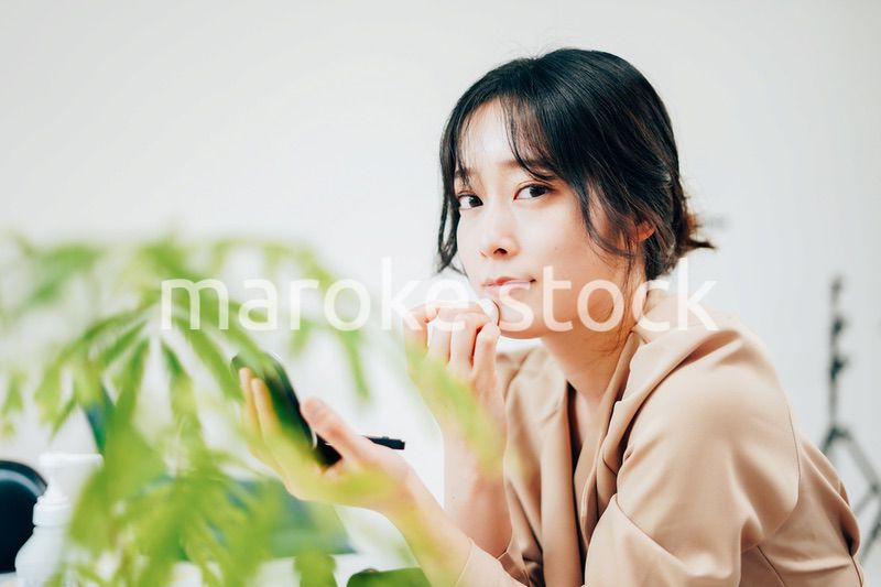 笑顔でメイクをする若い女性