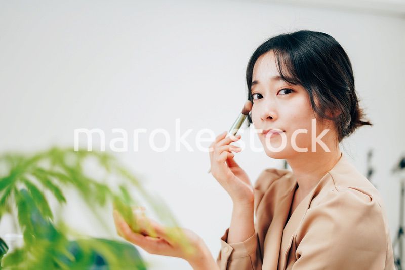 笑顔でメイクをする若い女性