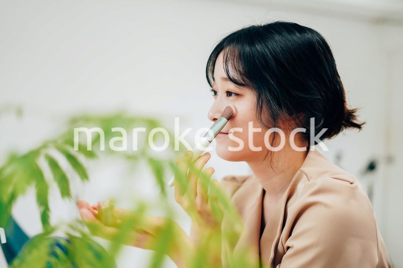 笑顔でメイクをする若い女性