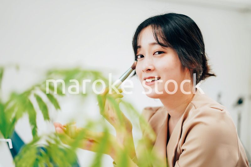 笑顔でメイクをする若い女性