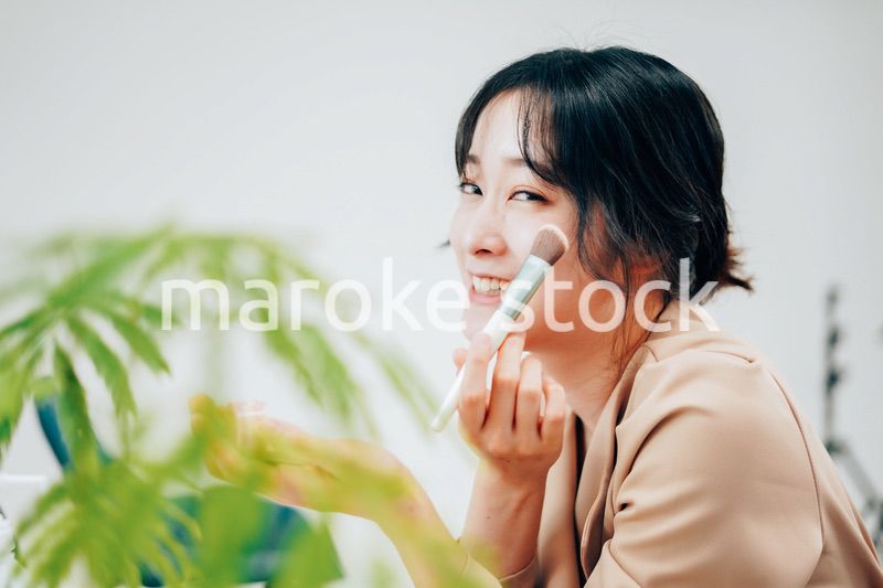 笑顔でメイクをする若い女性