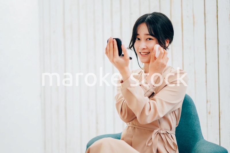 笑顔でメイクをする若い女性