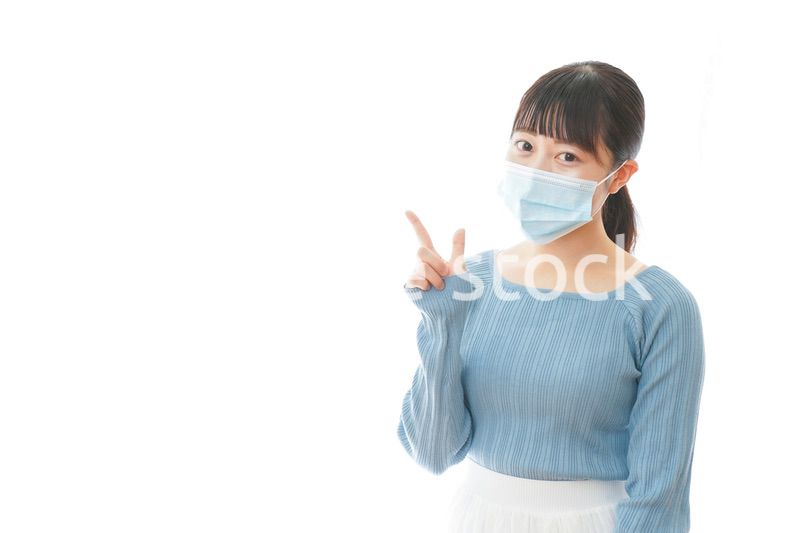 ポイントを指差すマスクを付けた若い女性