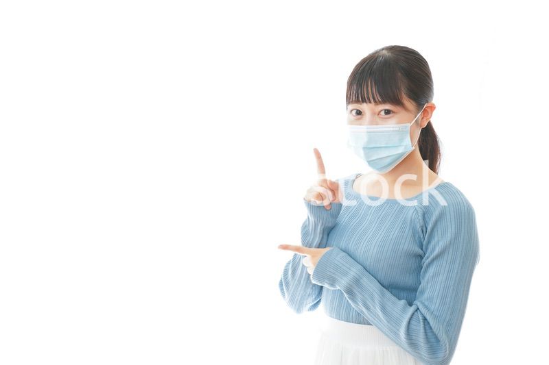 ポイントを指差すマスクを付けた若い女性