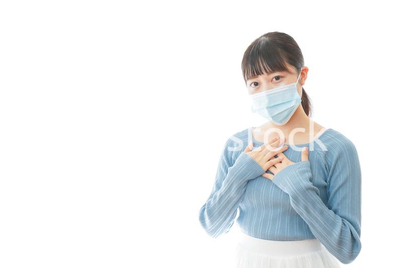 体調不良で苦しむマスクを付けた若い女性