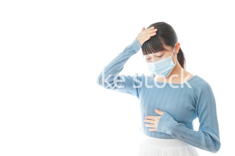 体調不良で苦しむマスクを付けた若い女性
